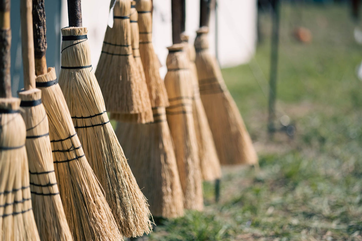 Rij bezems met houten stelen, klaar voor gebruik op het erf